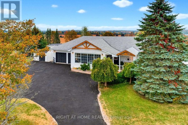 Aerial view of the white bungalow with a large evergreen tree in the foreground. - 31 Uxbridge Heights Drive, Brock