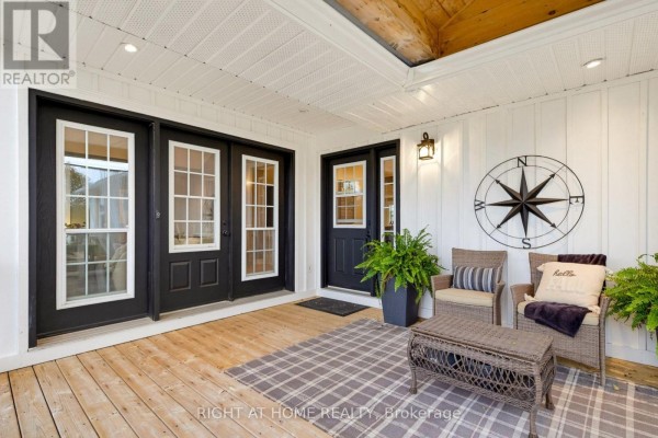 Covered porch with wicker furniture, a rug, and double black doors with glass. - 31 Uxbridge Heights Drive, Brock
