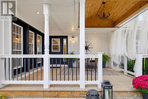 View of the covered porch with white railings, outdoor seating, and curtains. - 31 Uxbridge Heights Drive, Brock