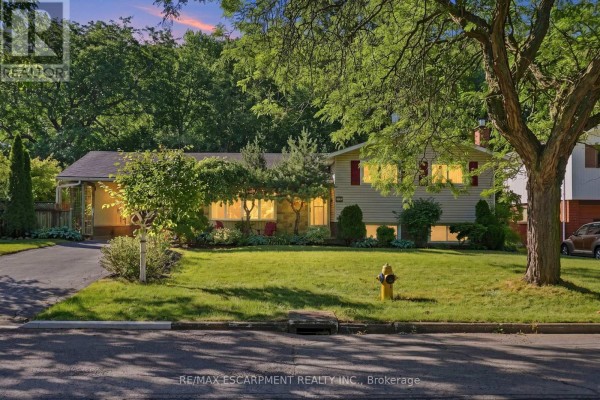 Exterior view of a residential house at dusk with warm interior lights and green trees. - 31 Valerie Drive, St  Catharines