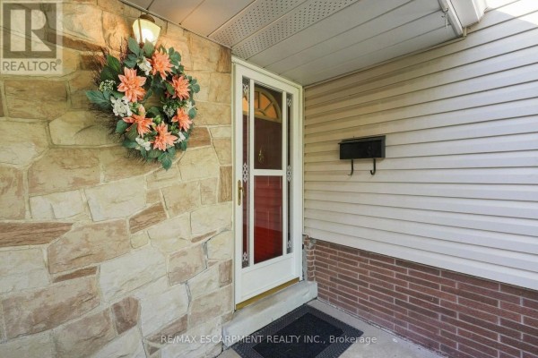 Front door with cream trim, decorative wreath, and a black mailbox on a stone and siding facade. - 31 Valerie Drive, St  Catharines