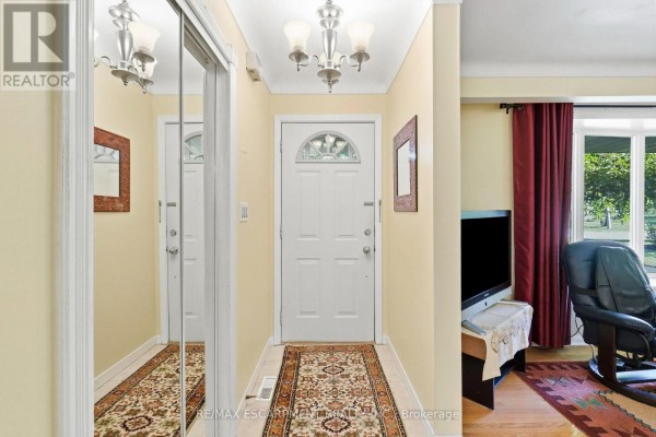 Interior hallway with cream walls, white door, mirrored closet, patterned runner, and chandelier. - 31 Valerie Drive, St  Catharines