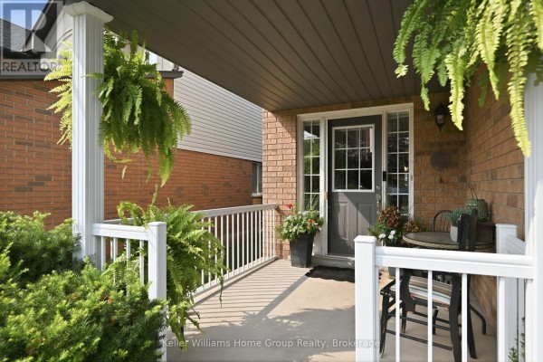 Covered front porch with white railings, hanging ferns, and a glass-paneled front door. - 31 Vinifera Drive, Grimsby