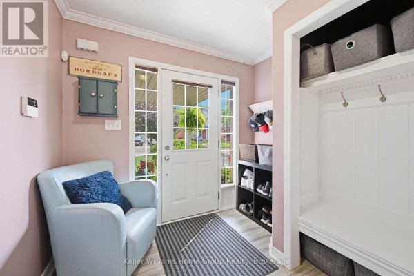 Interior entryway with pink walls, a light blue armchair, and a white built-in bench. - 31 Vinifera Drive, Grimsby