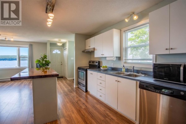 Open concept kitchen with white cabinets, stainless steel appliances, and water view. - 39 Water Street E, Harbour Grace
