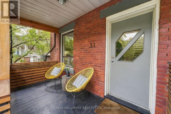 Close-up of the covered porch at 31 Wright Avenue, Toronto, featuring two yellow chairs and the front door. - 31 Wright Avenue, Toronto