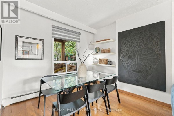Dining area with a glass table, black chairs, a window view, and modern wall art at 31 Wright Avenue, Toronto. - 31 Wright Avenue, Toronto