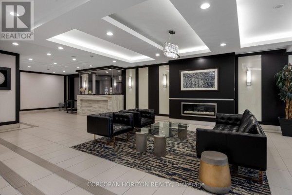 Lobby entrance with a reception desk, seating area, and decorative fireplace. - 310 - 1070 Sheppard Avenue W, Toronto