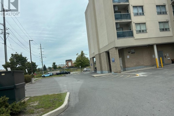 Side view of the apartment building with a parking lot and trees. - 310 - 160 Wellington Street E, Aurora
