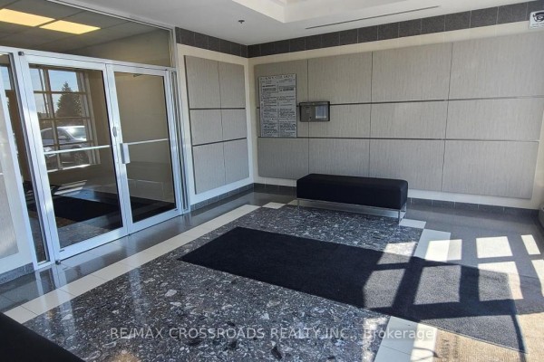 Interior building lobby with glass doors, dark bench, patterned walls, and granite floor. - 310 - 18 Crown Steel Drive, Markham