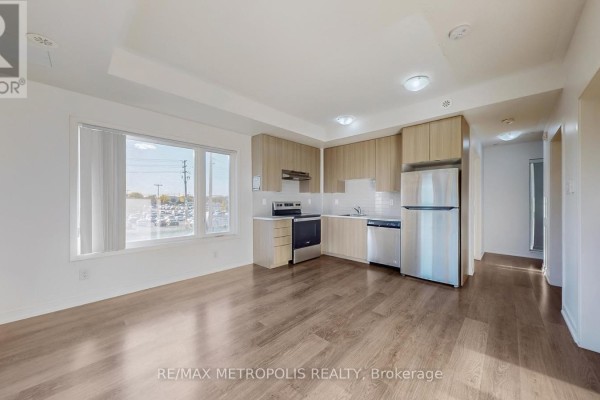 Apartment living area and kitchen with light wood cabinets, stainless steel appliances, and a large window. - 310 - 20 Orchid Place Drive, Toronto