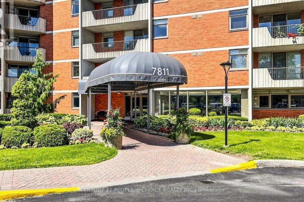 Covered entrance to the apartment building at 7811 Yonge Street with a ramp and landscaped bushes. - 310 - 7811 Yonge Street, Markham