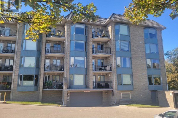 Apartment building side view showing balconies, windows, and an underground parking entrance. - 310 - 85 Wellington Street W, Aurora