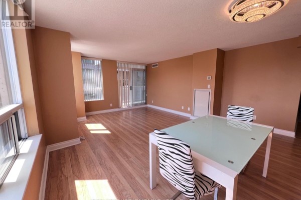 Living and dining area with a glass-top table, chairs, hardwood floors, and natural light. - 310 - 88 Times Avenue, Markham