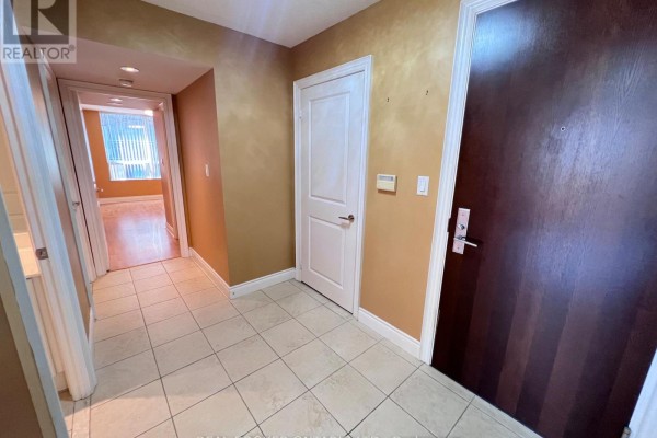 Hallway with tiled floor, white doors, and dark wood front door, leading to living area. - 310 - 88 Times Avenue, Markham