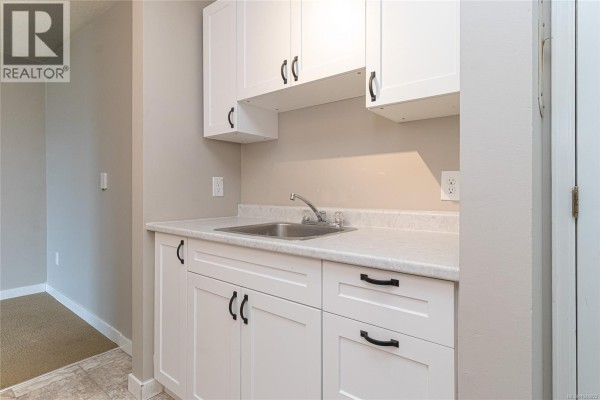 Interior view of a small kitchen area with white cabinets and a sink. - 310 2515 Alexander St, Duncan