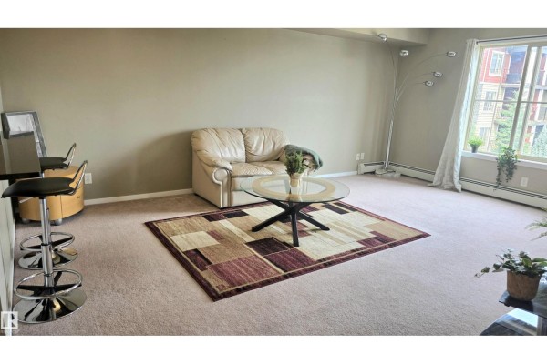 Dark wood kitchen cabinets, black appliances including a refrigerator and stove, and granite countertops. - #310 5370 Chappelle Rd Sw Sw, Edmonton