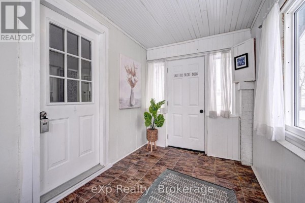 Entranceway with a white door, a staircase with dark wood banisters, and a large framed artwork. - 310 Barber Avenue N, North Perth