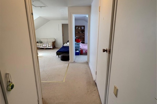 Interior hallway with carpeted floors, white walls, and doorways to rooms with beds. - 310 Main Street N, Ituna