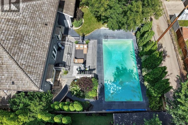 Overhead view of a backyard with a swimming pool, patio furniture, and lush green trees. - 310 Saskatchewan Crescent W, Saskatoon