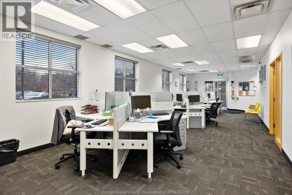 Long office area with multiple workstations, carpeted flooring, and bright lighting - 3100 Temple Drive, Windsor