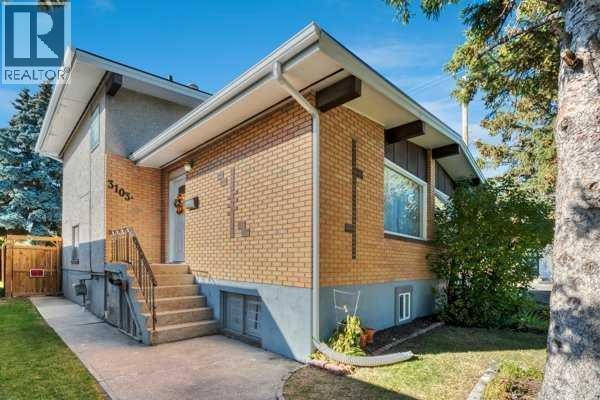 Front exterior of a duplex showing stairs to the main entrance and a brick facade. - 3103a 38 Street Sw, Calgary