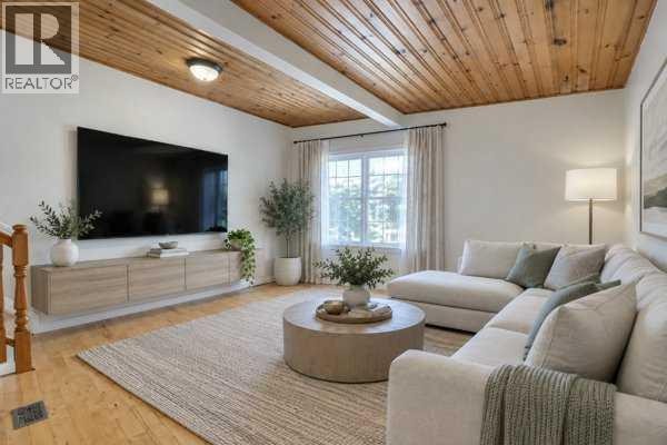 Living room with a large sectional sofa, round coffee table, and a mounted television. - 3103a 38 Street Sw, Calgary