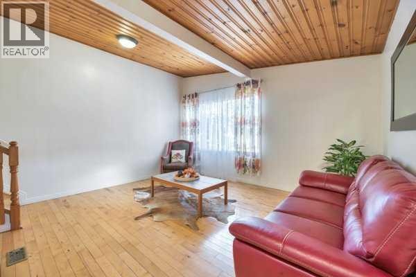 Living room with a red leather sofa, wooden coffee table, and a wood plank ceiling. - 3103a 38 Street Sw, Calgary