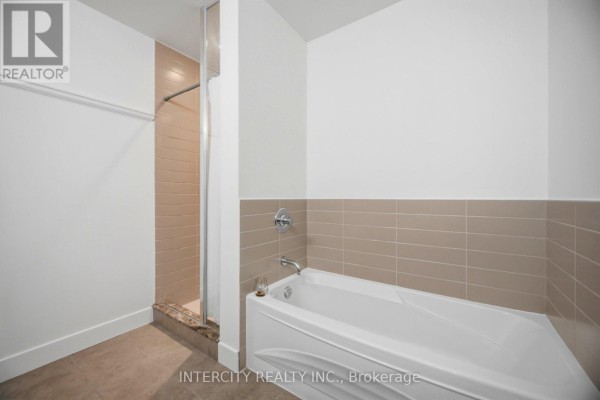 Bathroom with a white bathtub and a glass-enclosed shower with beige tiled walls. - 3104 - 23 Sheppard Avenue E, Toronto