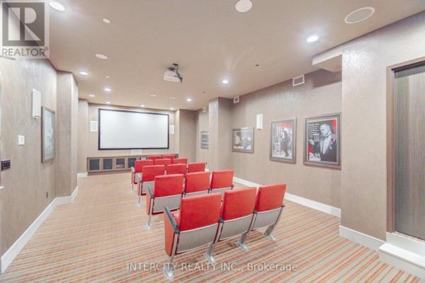 Home theatre room with red stadium seating, projector screen, and framed movie posters. - 3104 - 23 Sheppard Avenue E, Toronto