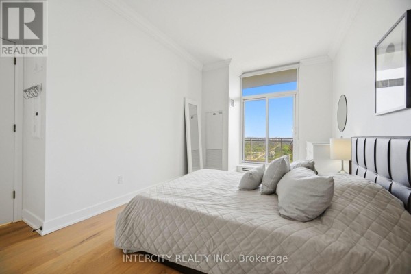 Bedroom with a king-size bed, white bedding, light wood floors, and a large window with a view. - 3104 - 23 Sheppard Avenue E, Toronto