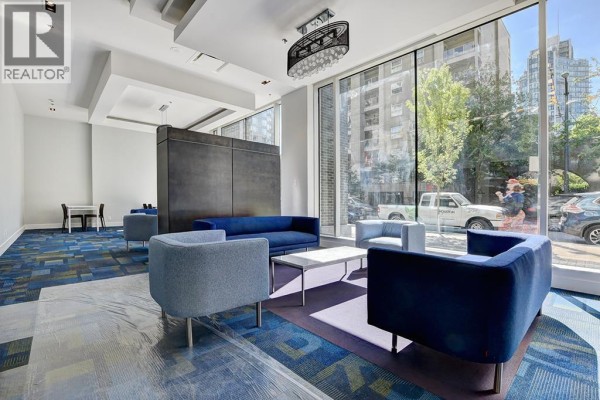 Building lobby with blue couches, armchairs, white coffee table, and a large window with city view. - 3104 1283 Howe Street, Vancouver