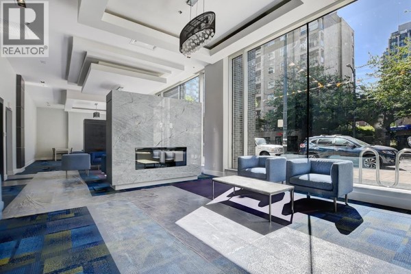 Building lobby with blue couches, fireplace, marble accent wall, and large window facing the street. - 3104 1283 Howe Street, Vancouver