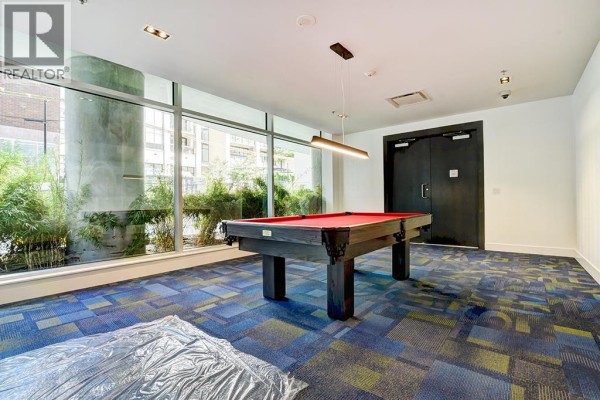 Billiard room with red pool table, large window with greenery, and blue patterned carpet. - 3104 1283 Howe Street, Vancouver