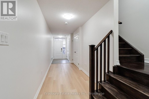Interior foyer with light wood flooring, white walls, and dark wood staircase. - 3105 Blackfriar Common, Oakville