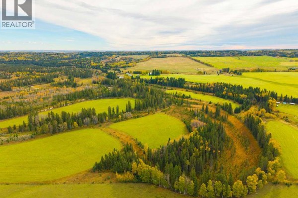 Aerial view of a winding river through a valley of green fields and dense coniferous forest in autumn. - 31064 Range Road 52, Rural Mountain View County