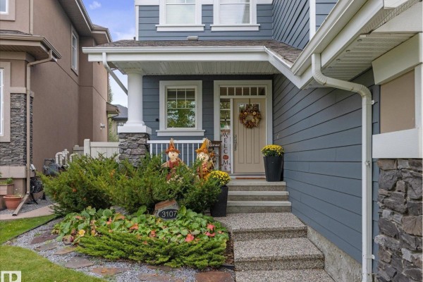 Front entrance porch with stone pillars, blue siding, and a tan door. - 3107 Cameron Heights Wy Nw, Edmonton