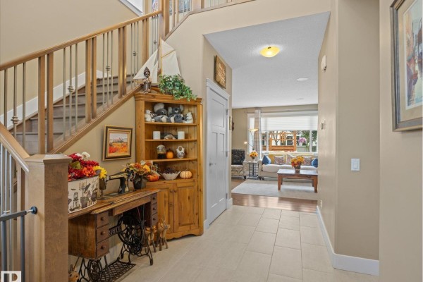 Foyer with a wooden staircase, antique sewing machine, corner cabinet, and view into living room. - 3107 Cameron Heights Wy Nw, Edmonton