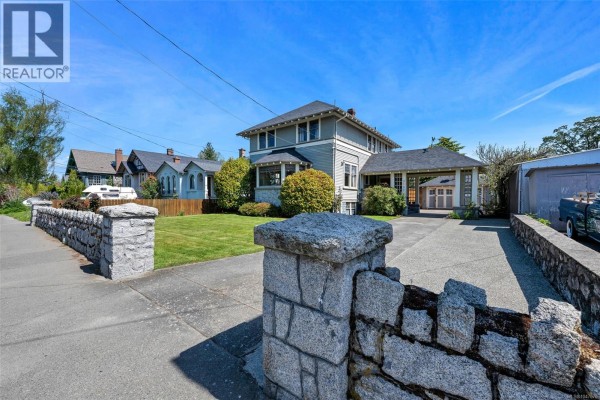 View of a blue house with a driveway, carport, and attached garage. - 3107 Quadra St, Victoria