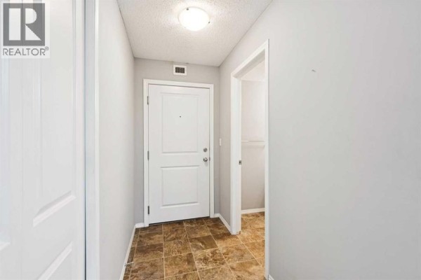 Apartment entryway with light grey walls, white door, and tiled floor. - 3108, 403 Mackenzie Way Sw, Airdrie