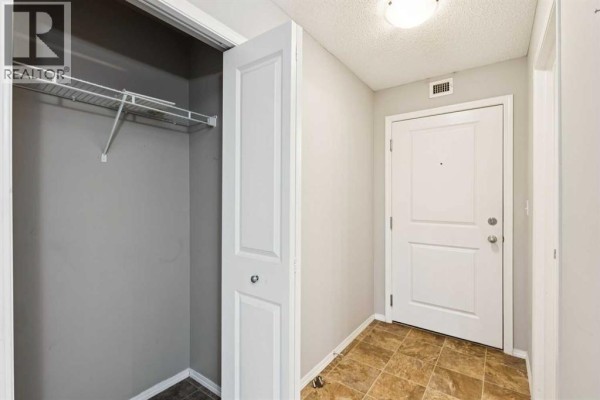 Apartment entryway showing a large closet with wire shelving and bi-fold doors. - 3108, 403 Mackenzie Way Sw, Airdrie