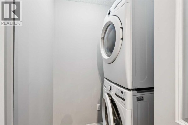 Stacked white front-load washer and dryer in a laundry closet. - 3108, 403 Mackenzie Way Sw, Airdrie