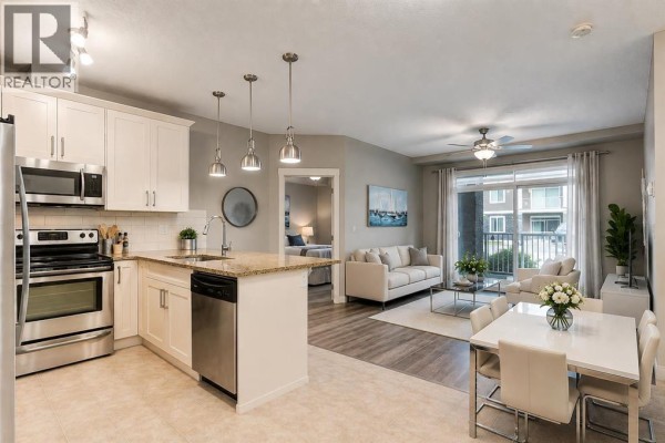 Kitchen with white cabinets, granite countertops, stainless steel appliances, and view into bedroom. - 3109, 522 Cranford Drive Se, Calgary