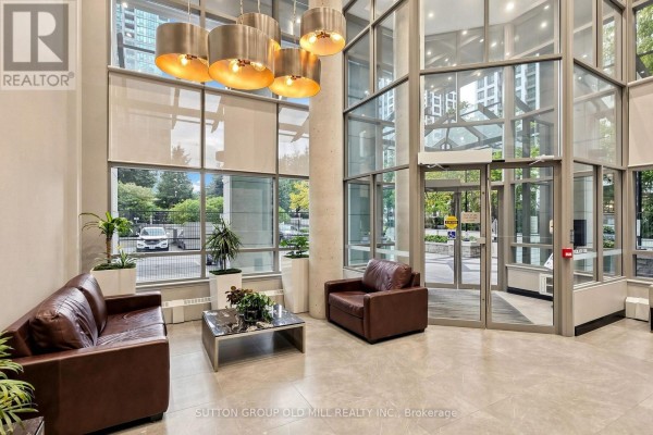 A modern building lobby with leather sofas, a chrome coffee table, and large windows. - 3109 - 3504 Hurontario Street, Mississauga