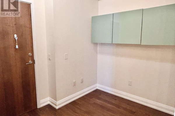 An empty entryway with a wooden door, beige walls, and light green cabinets. - 3109 - 3975 Grand Park Drive, Mississauga