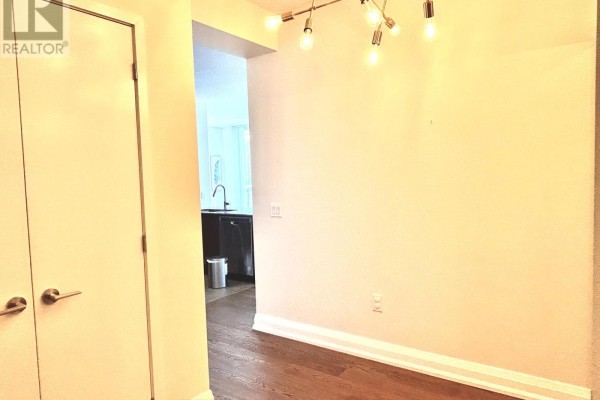 An interior view showing a hallway with doors, a kitchen in the background, and a modern light fixture. - 3109 - 3975 Grand Park Drive, Mississauga