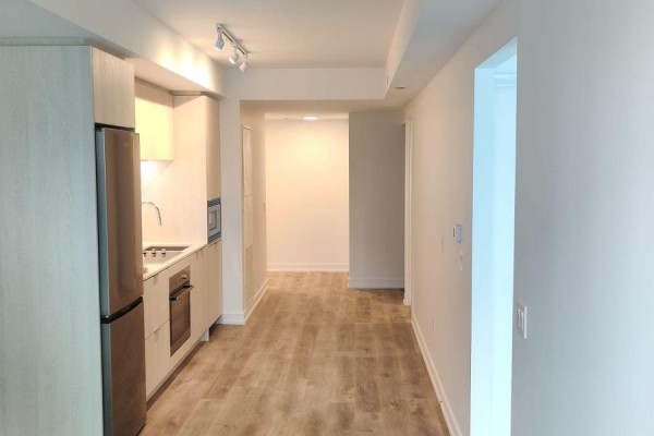 View down a hallway from the entryway of an apartment showing a modern kitchen on the left. - 311 - 1 Jarvis Street, Hamilton