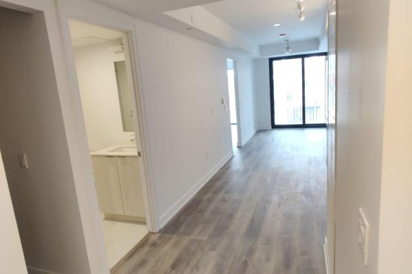 View of an apartment hallway with a glimpse into the bathroom and sliding glass doors to a balcony. - 311 - 1 Jarvis Street, Hamilton