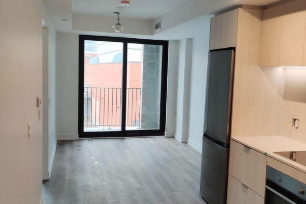 Living area with a balcony and a partial view of a modern kitchen with light wood cabinets. - 311 - 1 Jarvis Street, Hamilton