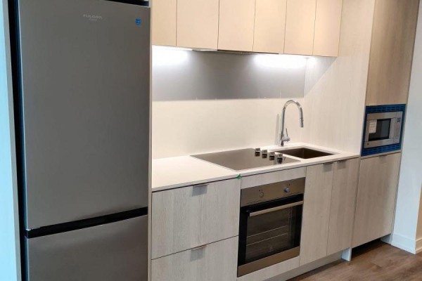 Close-up of a modern kitchen with light wood cabinets, stainless steel refrigerator, oven, and sink. - 311 - 1 Jarvis Street, Hamilton